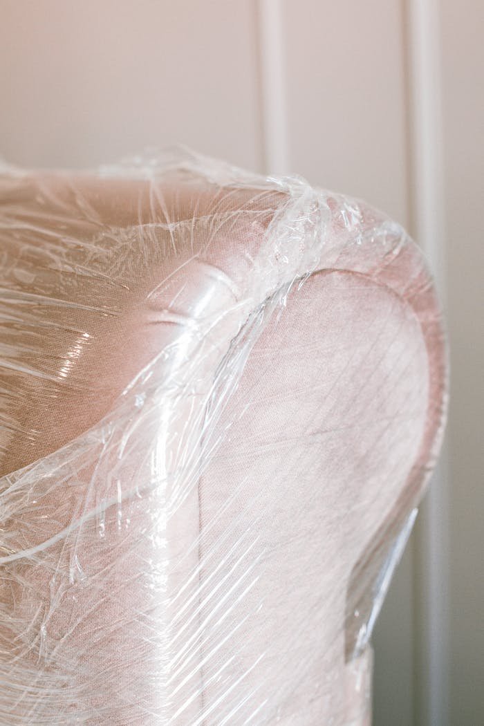 why-choose-us Close-up of a pink armchair covered in protective plastic wrap for moving.