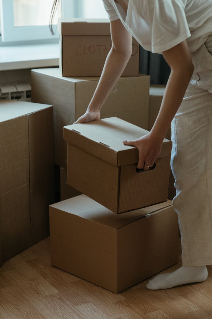 Services-02 A woman packing cardboard boxes in her new apartment, symbolizing moving and relocation.
